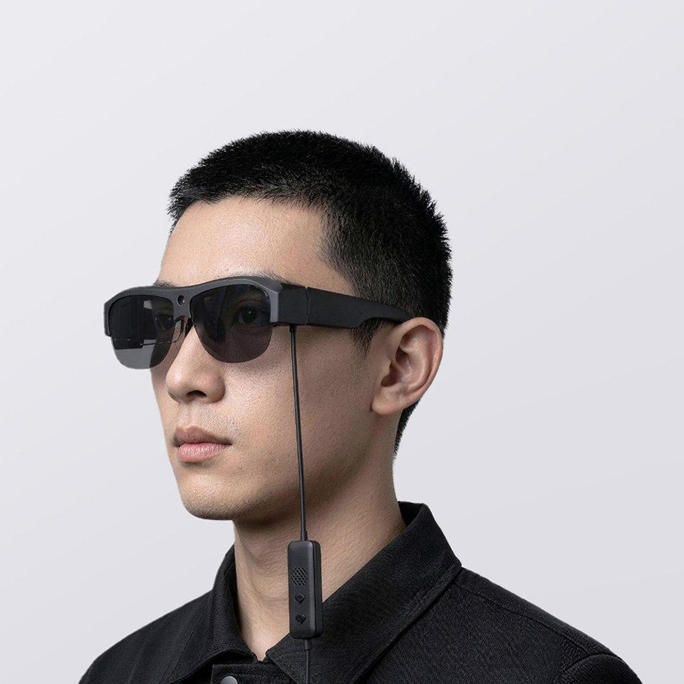 Model wearing Falcon 007 Pro glasses with the inline controller visible